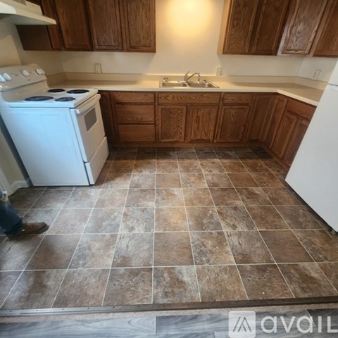 A kitchen with a white stove and brown cabinets.