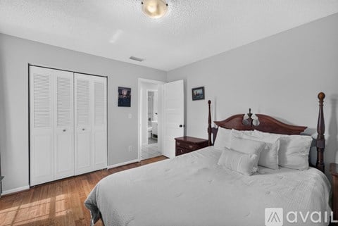 A bedroom with a large bed and a set of white closet doors.