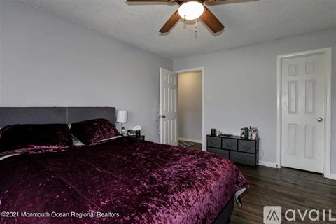 A bedroom with a bed covered in a purple velvet bedspread.