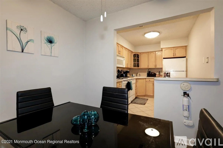 A kitchen with a table and chairs in the foreground and a view of the kitchen in the background.