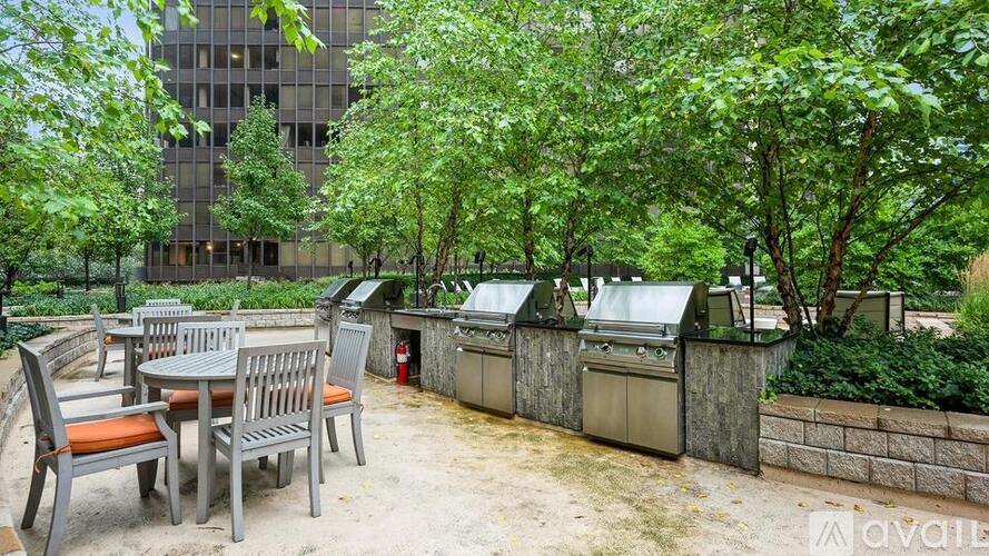 A patio with a table and chairs is surrounded by trees and a building.