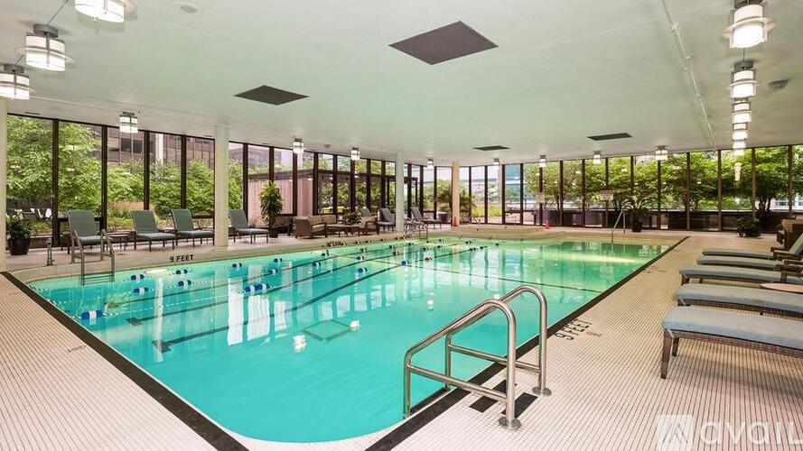 A large indoor swimming pool with people swimming and lounging by the poolside.