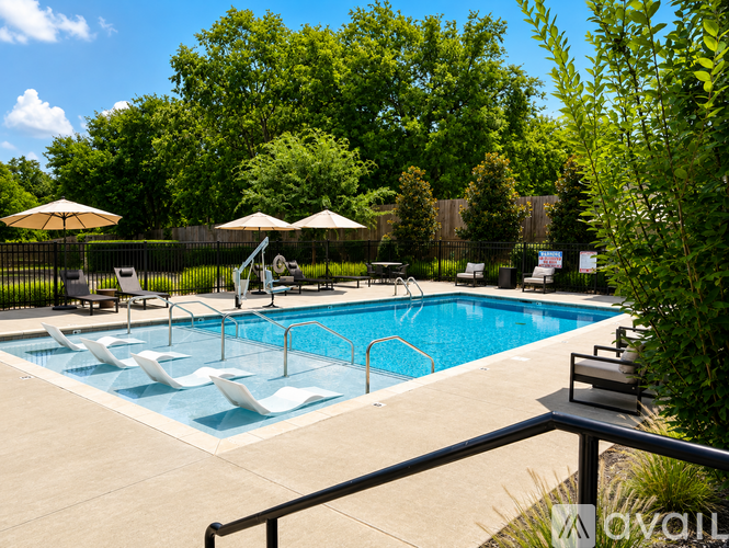 A pool surrounded by trees and chairs.