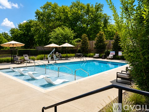 A pool surrounded by trees and chairs.