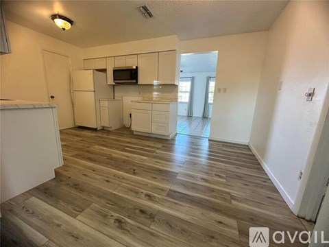 A kitchen area with wooden flooring and white appliances.
