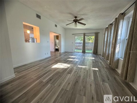 A spacious room with wooden flooring and a ceiling fan.
