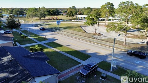 A street view of a residential area with houses, cars, and trees.