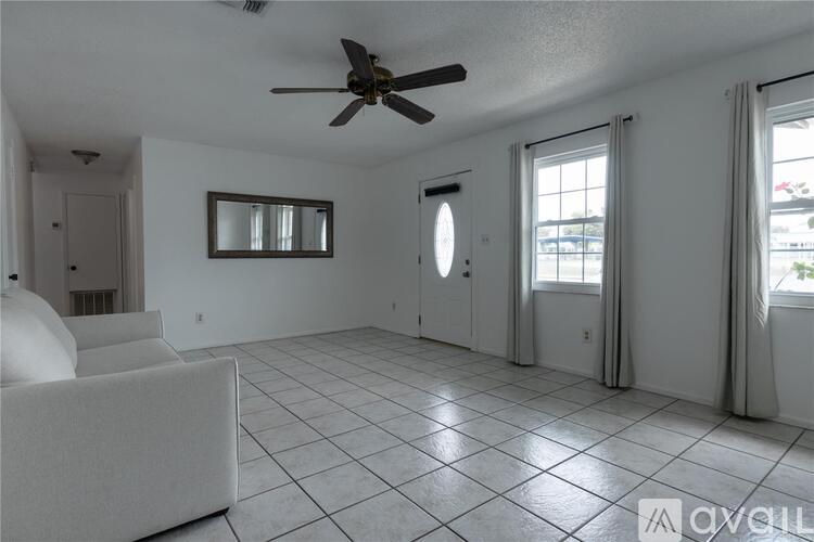 A spacious living room with a ceiling fan and a large white couch.
