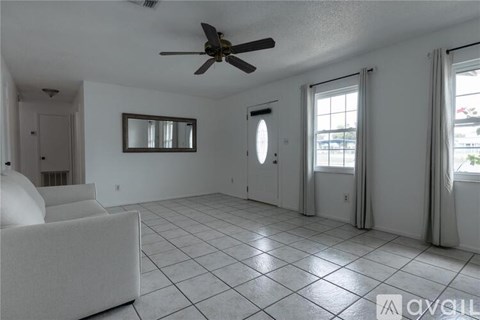 A spacious living room with a ceiling fan and a large white couch.