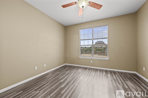 A room with a ceiling fan and a window overlooking a building.