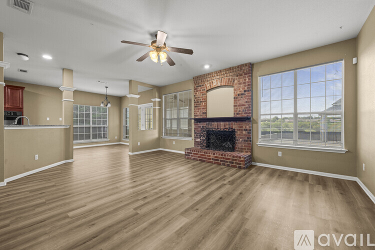 A spacious living room with a fireplace and a ceiling fan.
