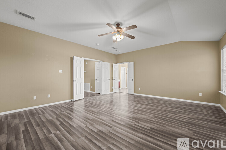 A spacious room with a ceiling fan and wooden flooring.