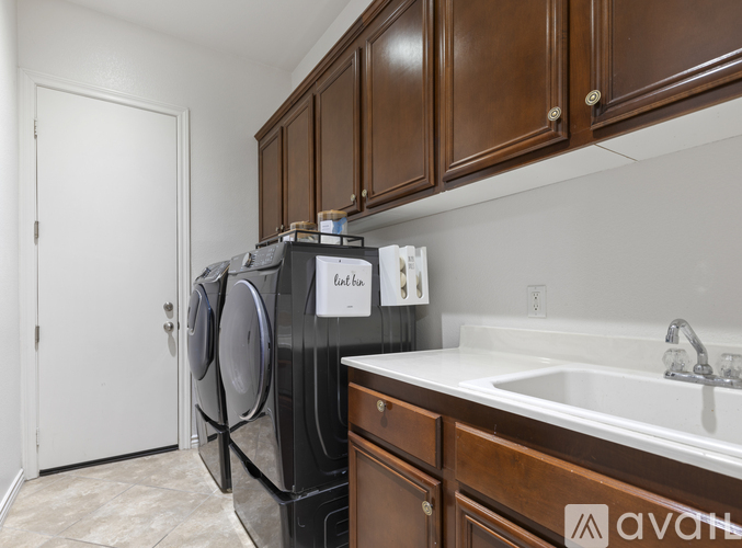 A black dishwasher is in a kitchen with brown cabinets.