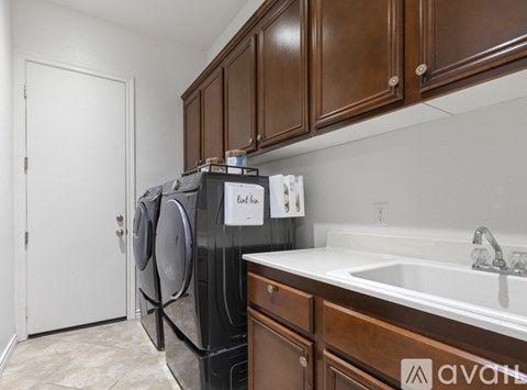 A black dishwasher is in a kitchen with brown cabinets.