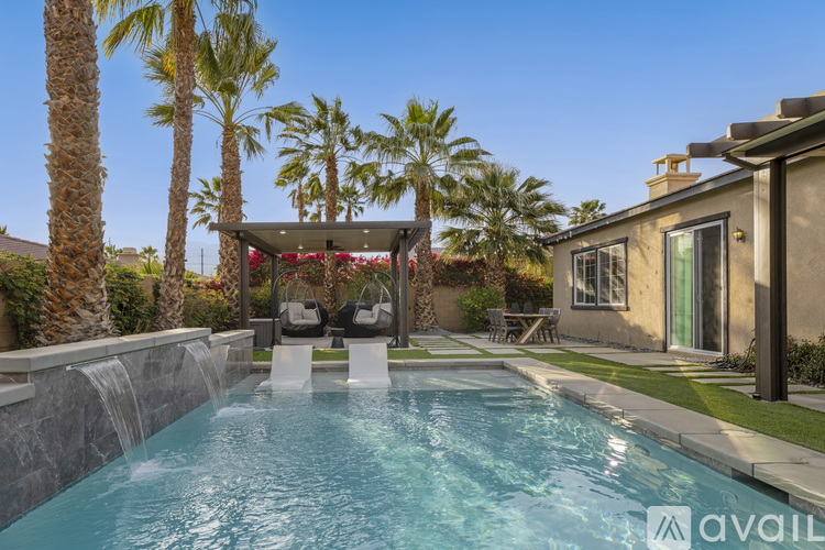 A pool with a waterfall and a gazebo in the background.