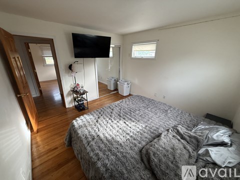 A bedroom with a bed, a TV, and a wooden floor.