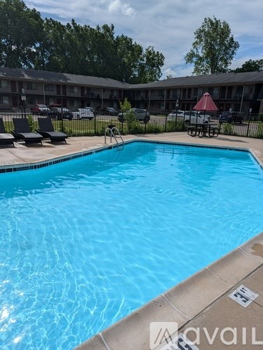 A swimming pool with a red umbrella and lounge chairs in the background.