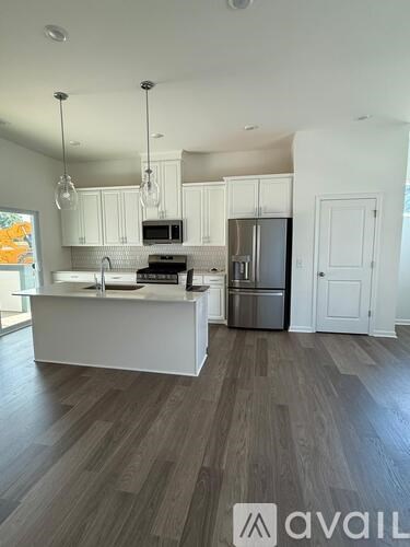 A kitchen with white cabinets and a wooden floor.