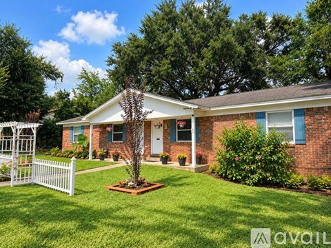 A house with a white picket fence and a tree in the front yard.