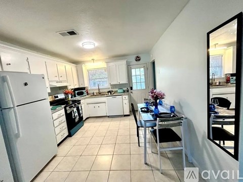 A kitchen with white appliances and a dining table with chairs.