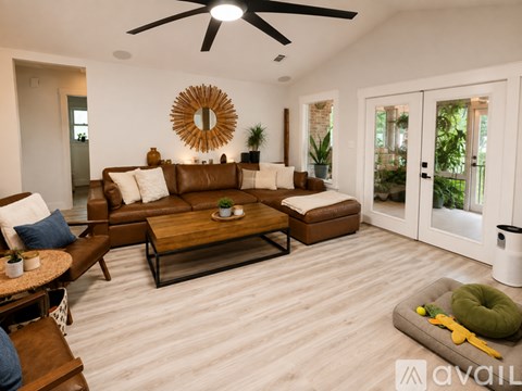 A living room with a brown couch, a coffee table, and a ceiling fan.