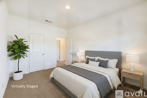 A bedroom with a large bed and a potted plant.