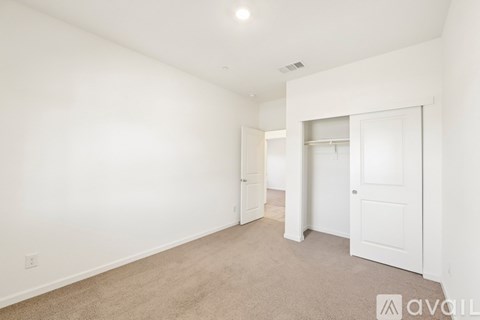A spacious room with white walls and carpeted floor.