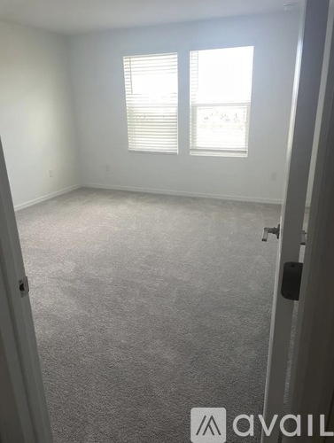 A carpeted room with a window and a door.