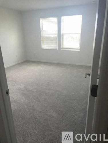 A carpeted room with a window and a door.