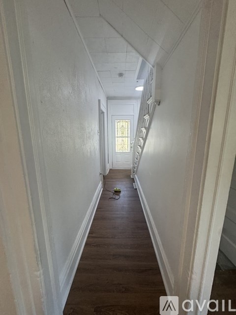 A long hallway with a staircase on the right and a door at the end.