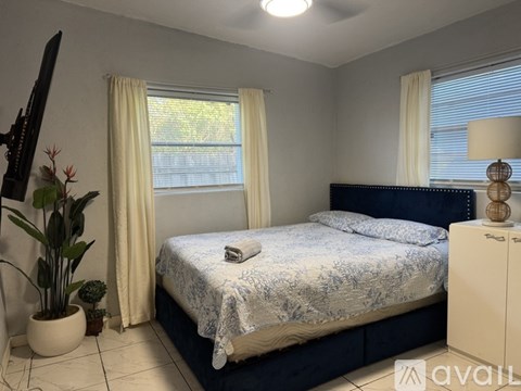 A bedroom with a bed, nightstand, and a plant.