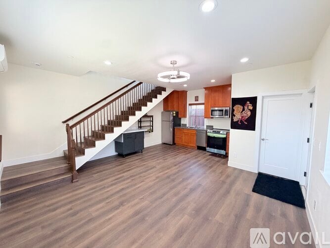 A spacious living room with a staircase and a kitchen area.