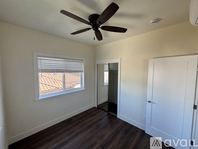 A room with a ceiling fan and a window with blinds.