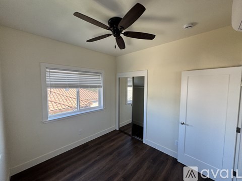 A room with a ceiling fan and a window with blinds.