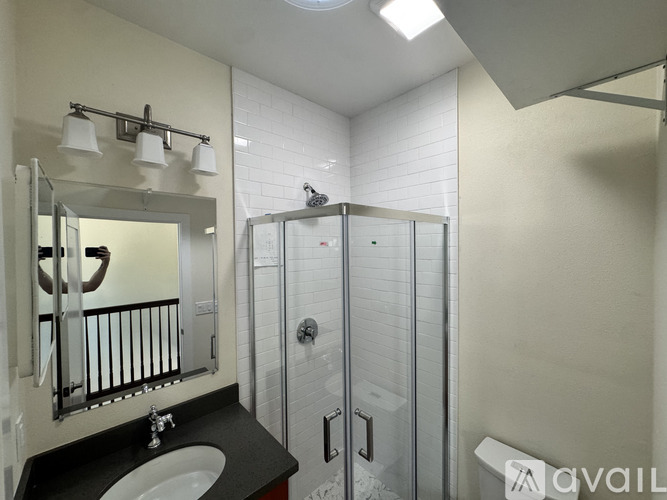 A bathroom with a sink, mirror, and shower.