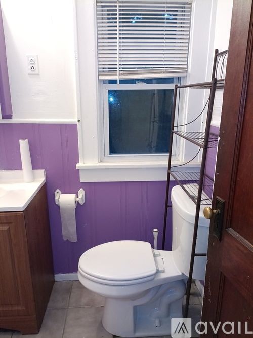 A white toilet in a bathroom with purple walls.