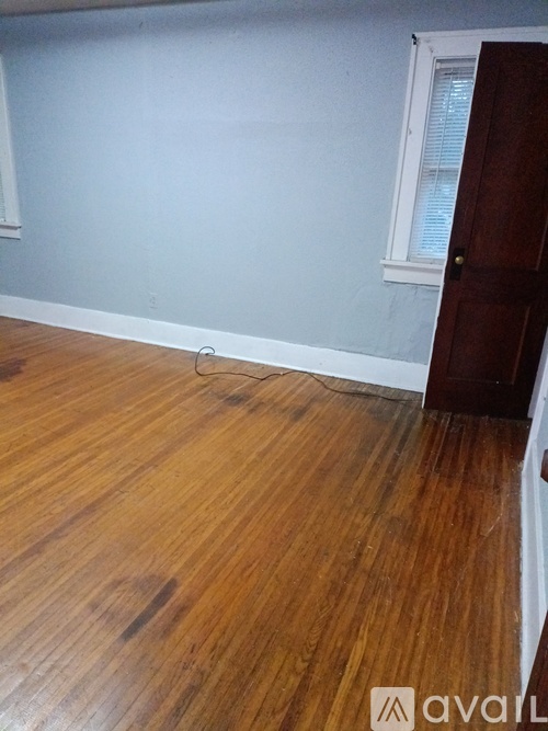 A room with wooden flooring and a door on the right.