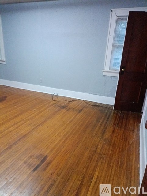 A room with wooden flooring and a door on the right.