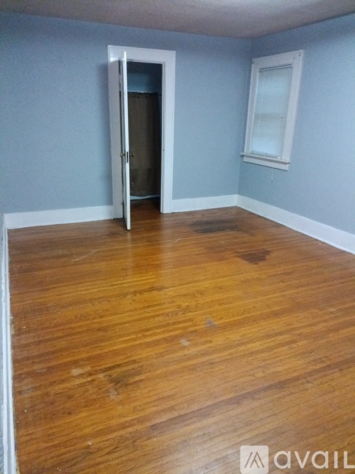 A room with a wooden floor and a door leading to another room.