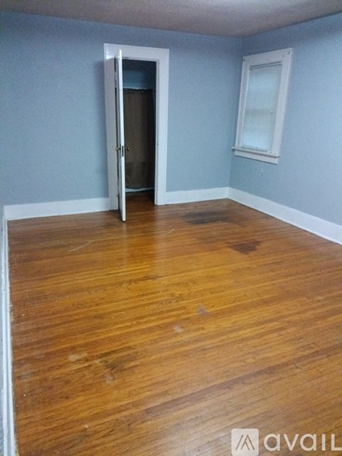 A room with a wooden floor and a door leading to another room.