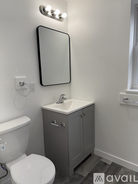 A bathroom with a toilet, sink, and mirror.