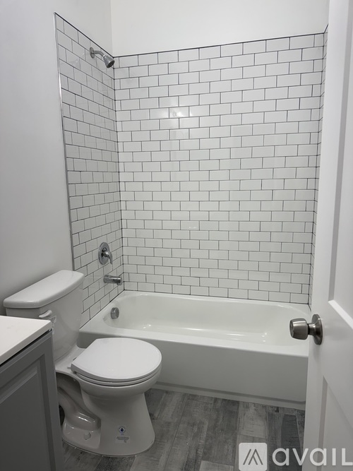 A white toilet sits next to a white bathtub in a bathroom with white tiled walls.