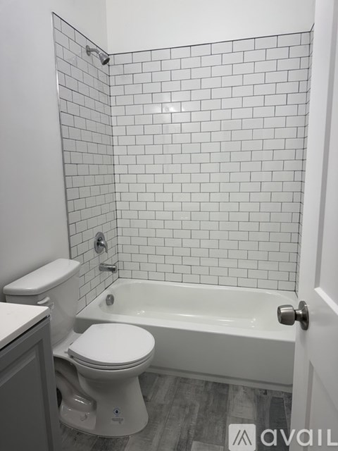 A white toilet sits next to a white bathtub in a bathroom with white tiled walls.