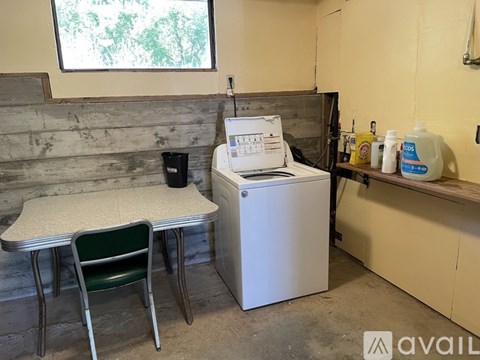 A white washer and dryer in a small room with a table and chair.