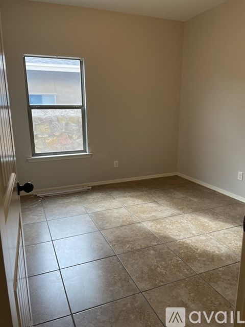 A room with beige walls and a tiled floor with a window.
