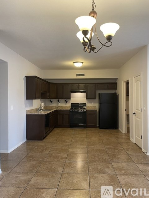 A kitchen with a black refrigerator and brown cabinets.