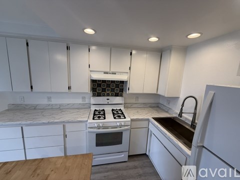 A kitchen with white cabinets and a stove top oven.
