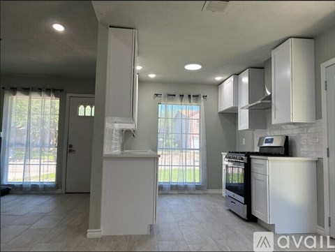 A kitchen with white cabinets and appliances is available for rent.