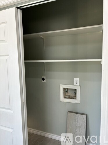 A white door is open to a small pantry with a picture frame on the wall.