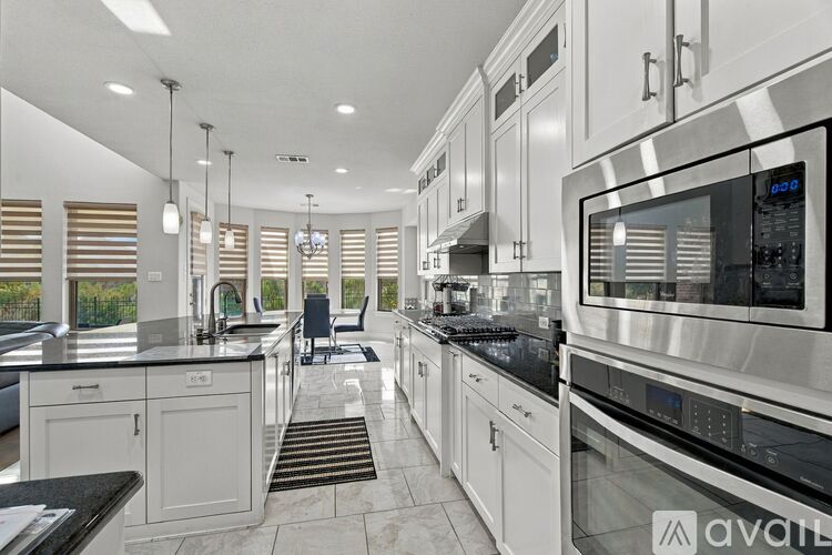 A modern kitchen with white cabinets and stainless steel appliances.